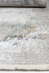 Detalle del borde enrollado y superficie con diseño artístico en azul y marrón sobre fondo claro.