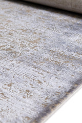 Detalle lateral de la alfombra enrollada, destacando el diseño ornamental en relieve.