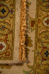 Detalle de alfombra doblada mostrando textura, grosor, flecos y combinación de figuras florales en una paleta neutra y cálida