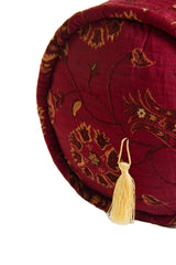 Detalle de textura de almohadón caramelo bordó con diseño floral y borla decorativa dorada
