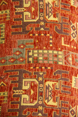 Detalle del diseño geométrico del almohadón en tonos marrón, rojo, beige y verde