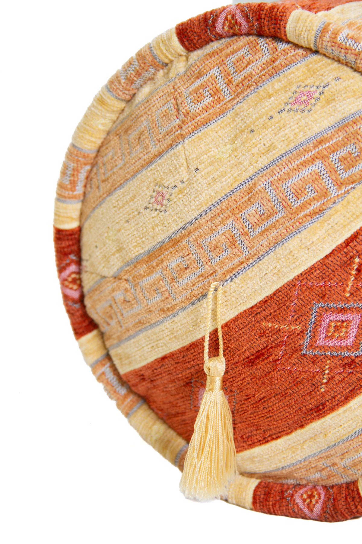 Detalle de textura de almohadón caramelo amarillo con rayas, rombos y borla decorativa