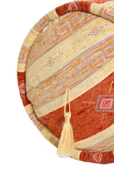 Detalle de textura de almohadón caramelo amarillo con rayas, rombos y borla decorativa