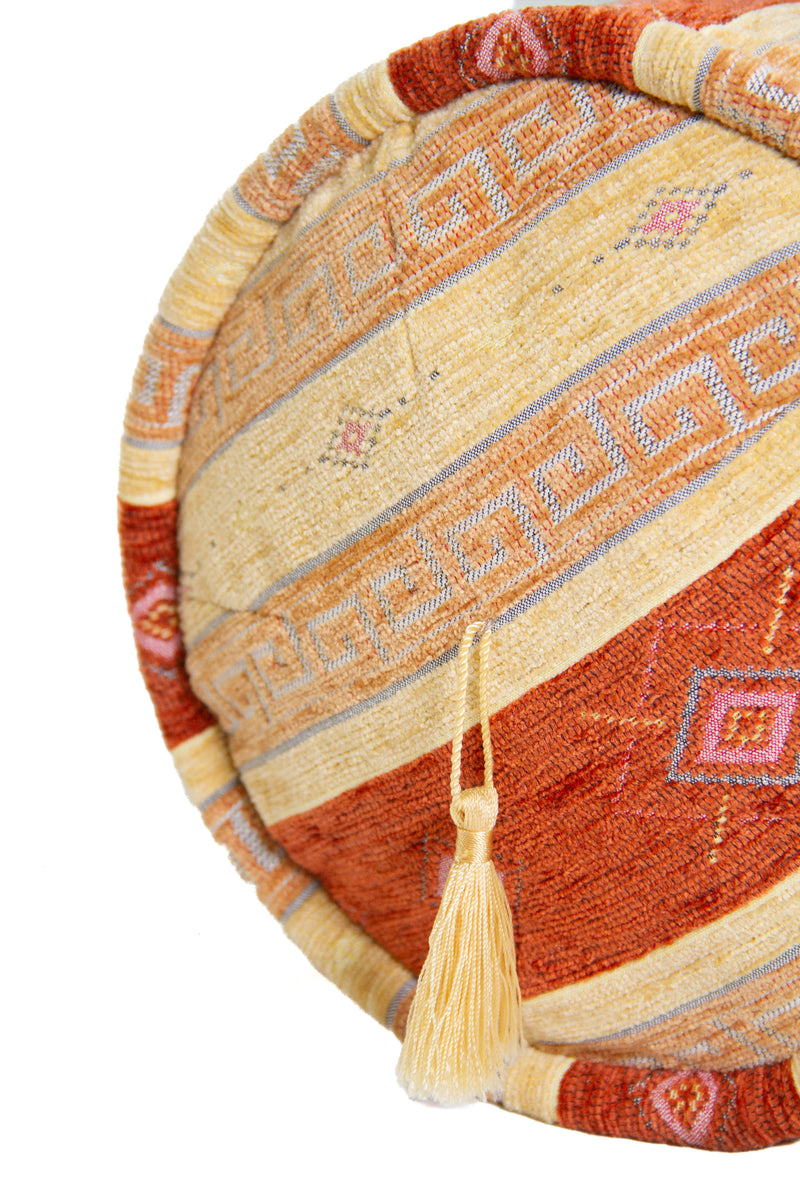 Detalle de textura de almohadón caramelo amarillo con rayas, rombos y borla decorativa