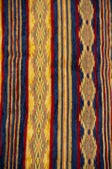 Detalle del diseño textil con rayas azules, amarillas y rojas en almohadón caramelo