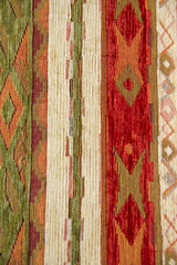 Detalle del diseño rayado y geométrico del almohadón en tonos verde, rojo y beige