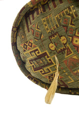Detalle de textura de almohadón caramelo verde con motivos geométricos y borla decorativa