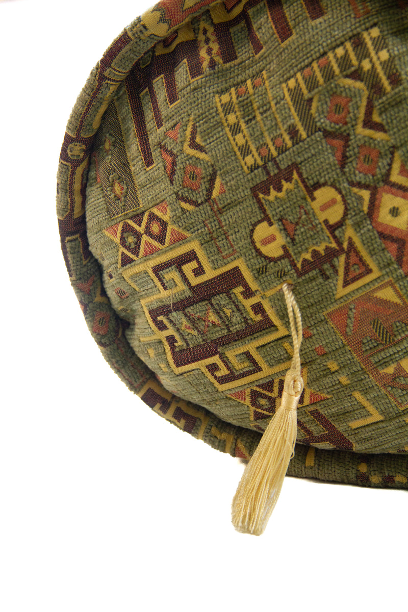 Detalle de textura de almohadón caramelo verde con motivos geométricos y borla decorativa