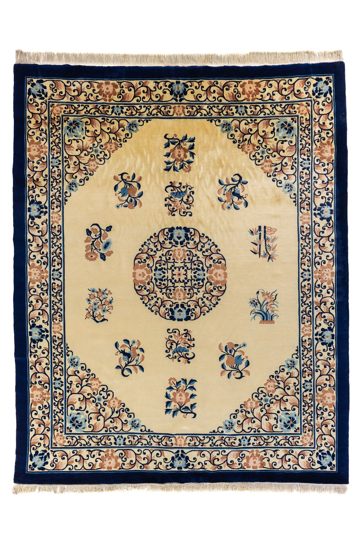 Alfombra clásica de fondo beige con medallón circular central y guarda azul marino con flores y arabescos.