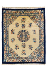 Alfombra clásica de fondo beige con medallón circular central y guarda azul marino con flores y arabescos.