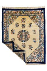 Alfombra beige y azul marino con esquina levantada, mostrando el reverso, flecos y acabado del tejido.