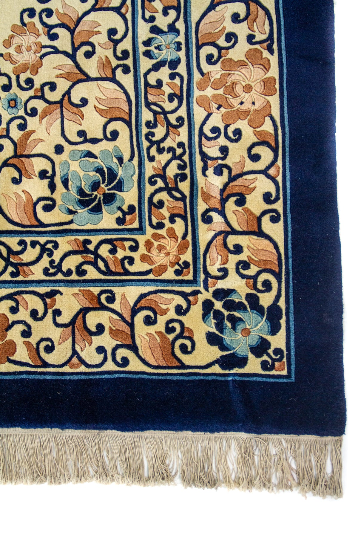 Detalle de la guarda azul marino con flores en tonos celeste y marrón, más flecos beige en el borde.