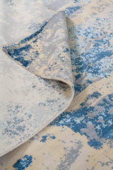 Detalle del reverso y textura de alfombra rectangular beige y azul con diseño abstracto