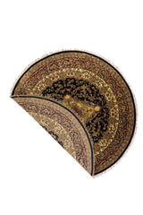 Alfombra redonda plegada mostrando su flexibilidad, diseño ornamental y acabado con flecos.