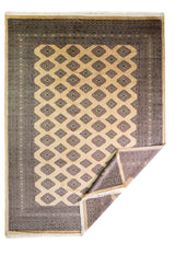 Alfombra Persa Bukara Yamouth marrón y beige de 2.25 x 3.25 mts, vista completa con una esquina doblada, mostrando el reverso y la guarda; se observan retícula geométrica clara sobre campo oscuro