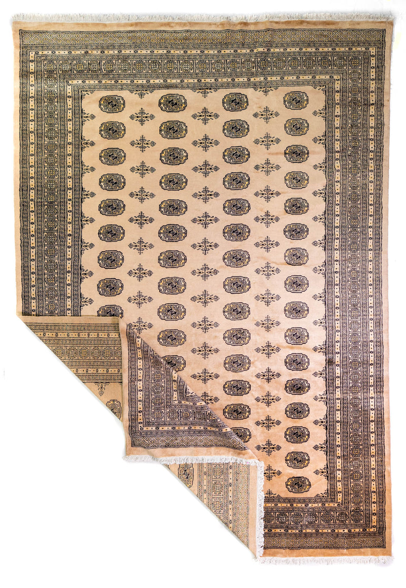 Alfombra Persa Bukara Yamouth beige de 2.19 x 3.00 mts, vista completa con una esquina doblada; se observan medallones ovalados repetidos dentro de una composición ordenada