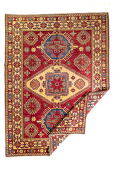 Alfombra Caucasica Kazak rojo y beige de 2.77 x 2.08 mts, vista completa con una esquina doblada; se observan medallones y motivos geométricos caucásicos de fuerte contraste