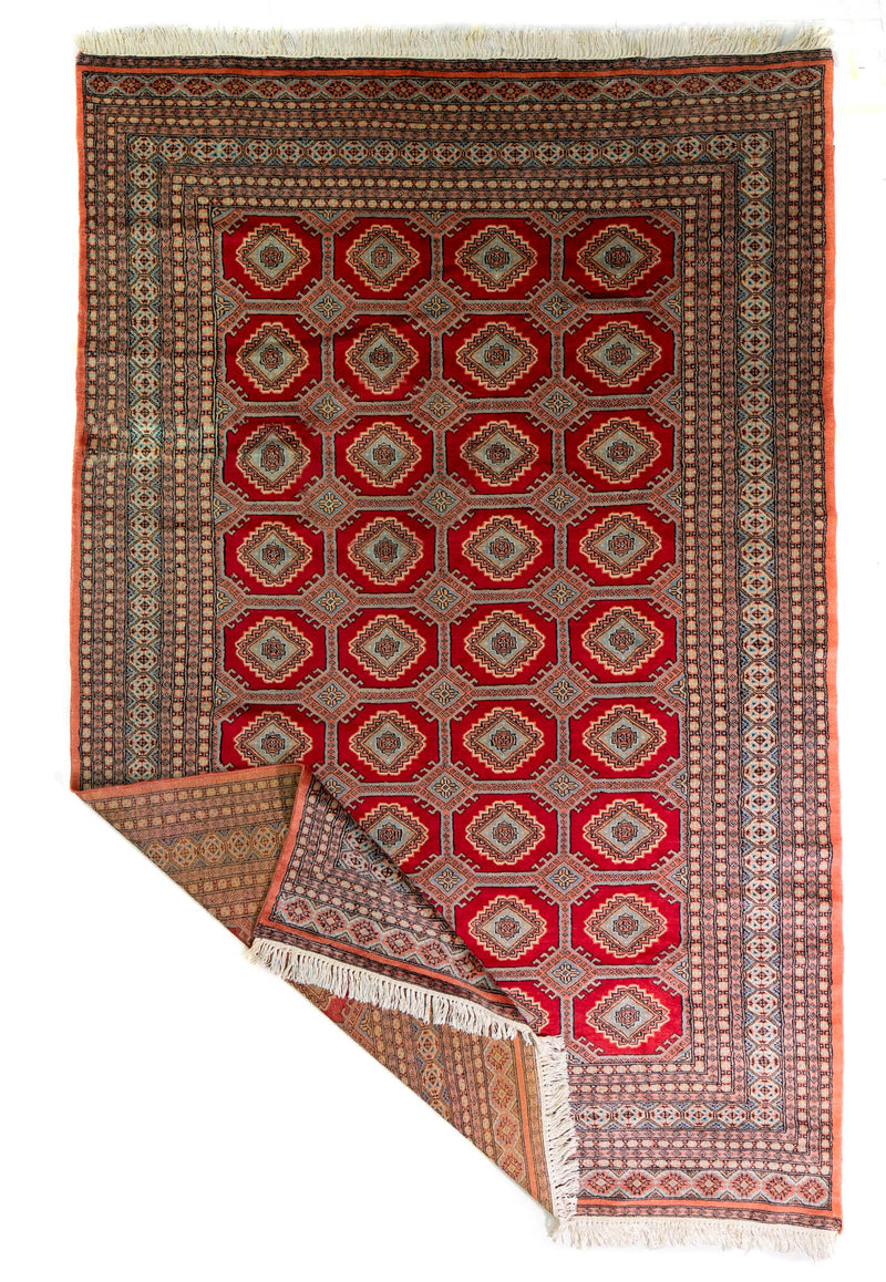 Alfombra Persa Bukara Yamouth rojo de 3.00 x 2.00 mts, vista completa con una esquina doblada; se observan medallones geométricos repetidos y guardas ornamentales