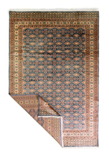 Alfombra Persa Bukara Yamouth celeste de 1.88 x 2.85 mts, vista completa con una esquina doblada; se observan motivos pequeños repetidos y guardas geométricas contrastantes