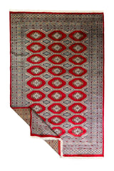Alfombra Persa Bukara Yamouth rojo de 1.90 x 2.90 mts, vista completa con una esquina doblada; se observan medallones ovalados repetidos y guardas de varios niveles
