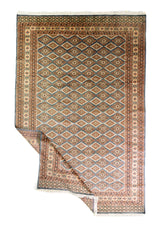 Alfombra Persa Bukara Yamouth celeste de 1.88 x 2.87 mts, vista completa con una esquina doblada; se observan rombos repetidos y guardas geométricas
