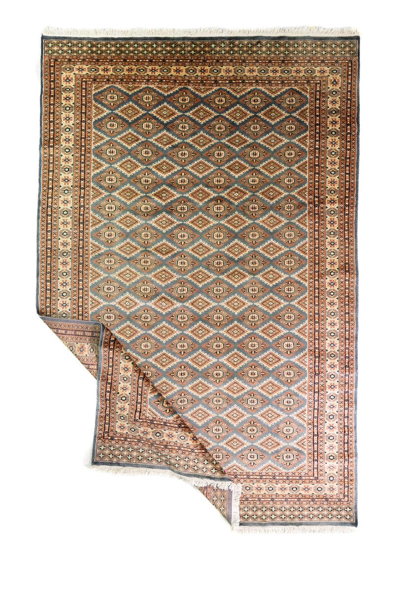 Alfombra Persa Bukara Yamouth celeste de 1.88 x 2.87 mts, vista completa con una esquina doblada; se observan rombos repetidos y guardas geométricas