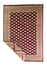Alfombra Persa Bukara Yamouth bordó de 1.88 x 2.75 mts, vista completa con una esquina doblada; se observan entramado geométrico oscuro y guardas claras