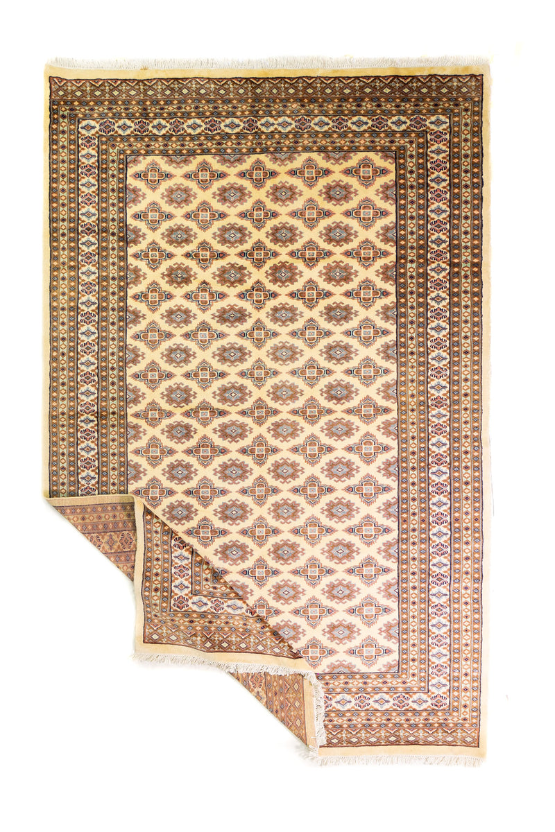 Alfombra Persa Bukara Yamouth beige de 1.88 x 2.90 mts, vista completa con una esquina doblada; se observan retícula geométrica con detalles de color en las guardas