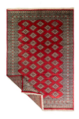 Alfombra Persa Yamouth rojo de 1.81 x 2.87 mts, vista completa con una esquina doblada; se observan medallones y rombos repetidos en una trama geométrica