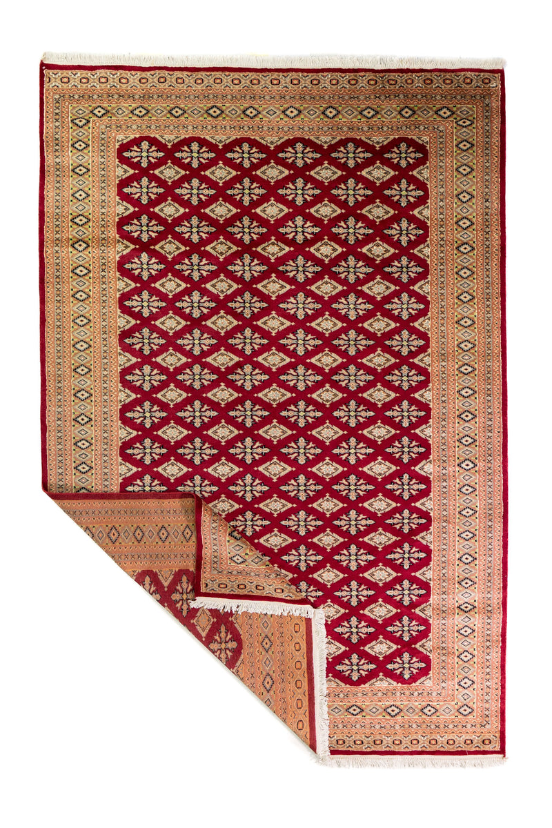 Alfombra Persa Yamouth rojo de 1.88 x 2.80 mts, vista completa con una esquina doblada; se observan retícula geométrica densa con guarda ornamental