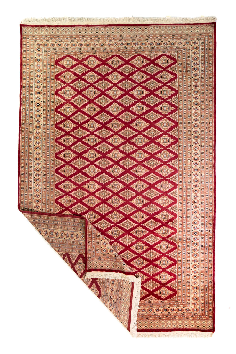Alfombra Persa Yamouth rojo de 1.83 x 2.87 mts, vista completa con una esquina doblada; se observan patrón geométrico repetitivo con guardas ornamentales