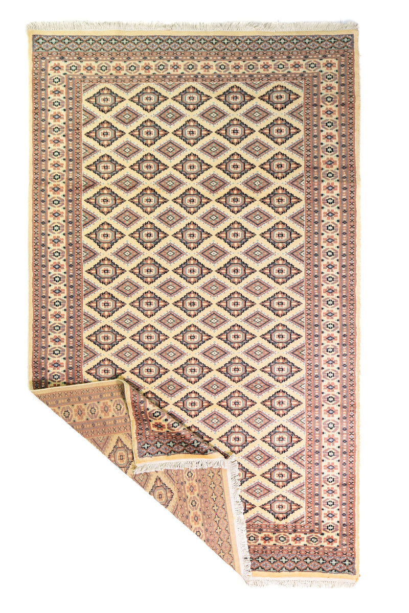 Alfombra Persa Yamouth beige de 1.55 x 2.54 mts, vista completa con una esquina doblada; se observan rombos repetidos y guardas geométricas de contraste