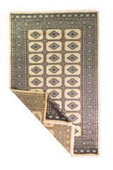 Alfombra Persa Yamouth beige de 1.55 x 2.44 mts, vista completa con una esquina doblada; se observan medallones rectangulares repetidos y guardas oscuras