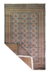Alfombra Persa Yamouth celeste de 1.55 x 2.48 mts, vista completa con una esquina doblada; se observan rombos repetidos y guardas geométricas