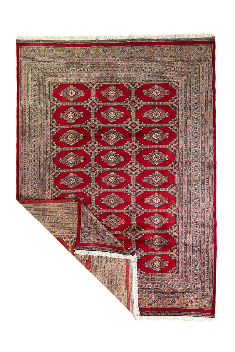 Alfombra Persa Yamouth rojo de 1.58 x 2.36 mts, vista completa con una esquina doblada; se observan medallones ovalados destacados y guardas rojizas