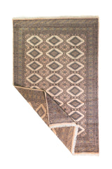 Alfombra Persa Yamouth marrón y beige de 1.52 x 2.44 mts, vista completa con una esquina doblada; se observan grandes rombos claros y guardas oscuras