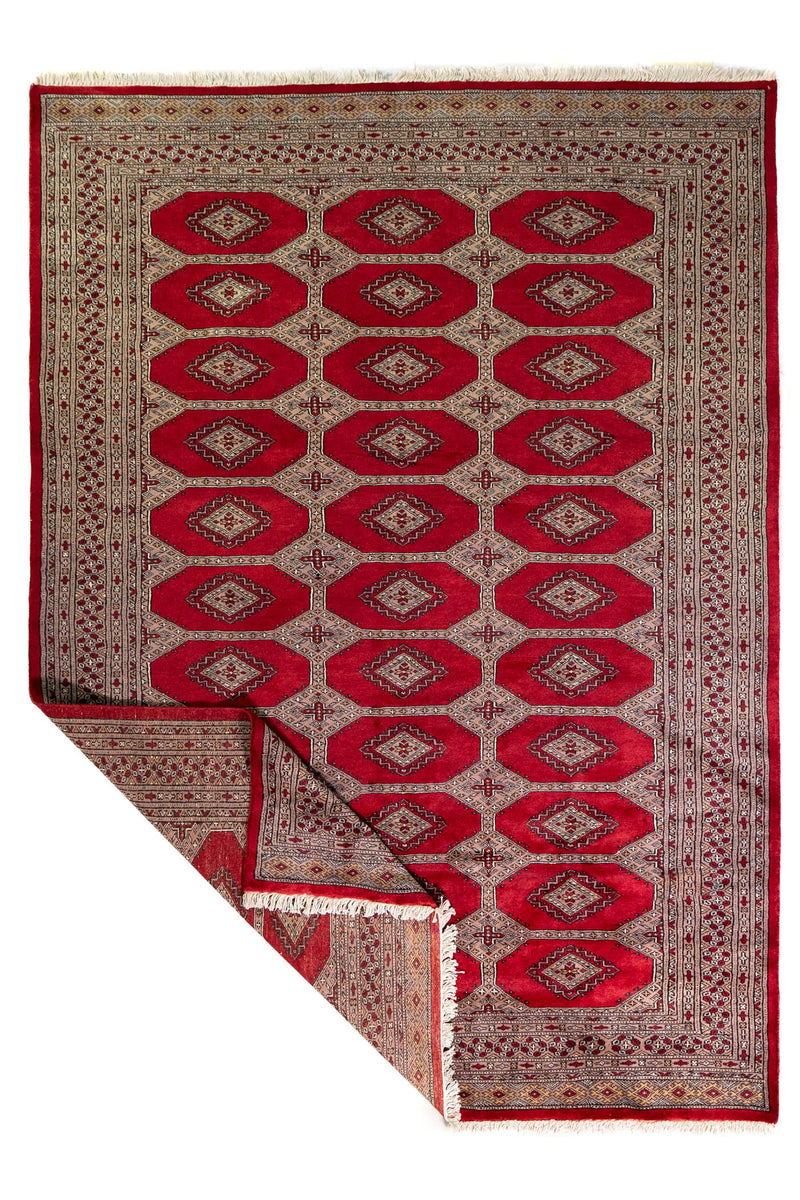 Alfombra Persa Yamouth rojo de 1.70 x 2.37 mts, vista completa con una esquina doblada; se observan medallones ovalados repetidos y guardas contrastantes