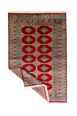 Alfombra Persa Bukara Yamouth rojo de 1.27 x 2.00 mts, vista completa con una esquina doblada; el diseño muestra medallones geométricos repetidos en dos columnas y un marco ornamental de alto contraste