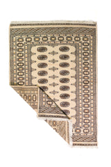 Alfombra Persa Bukara Yamouth beige de 1.24 x 1.73 mts, vista completa con una esquina doblada; el diseño muestra medallones ovalados oscuros alineados sobre un campo claro y guardas geométricas profundas