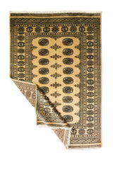 Alfombra Persa Bukara Yamouth beige de 1.24 x 1.93 mts, vista completa con una esquina doblada; el diseño muestra medallones ovalados oscuros sobre un campo beige y un marco de guardas geométricas