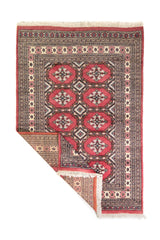 Alfombra Persa Yamouth rosa de 1.28 x 1.88 mts, vista completa con una esquina doblada; el diseño muestra medallones rosados repetidos sobre un campo oscuro y un borde ornamental detallado