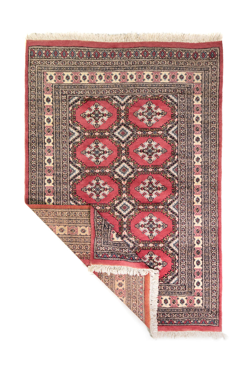 Alfombra Persa Yamouth rosa de 1.28 x 1.88 mts, vista completa con una esquina doblada; el diseño muestra medallones rosados repetidos sobre un campo oscuro y un borde ornamental detallado