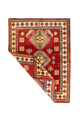 Alfombra Caucasica Kazak rojo y beige de 1.17 x 1.58 mts, vista completa con una esquina doblada; el diseño muestra tres grandes medallones geométricos sobre un campo rojo y guardas claras con pequeños acentos