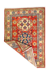 Alfombra Caucasica Kazak ladrillo con detalles multicolor de 1.24 x 1.78 mts, vista completa con una esquina doblada; el diseño muestra medallones y motivos geométricos de gran contraste distribuidos sobre un campo ladrillo con bordes multicolores