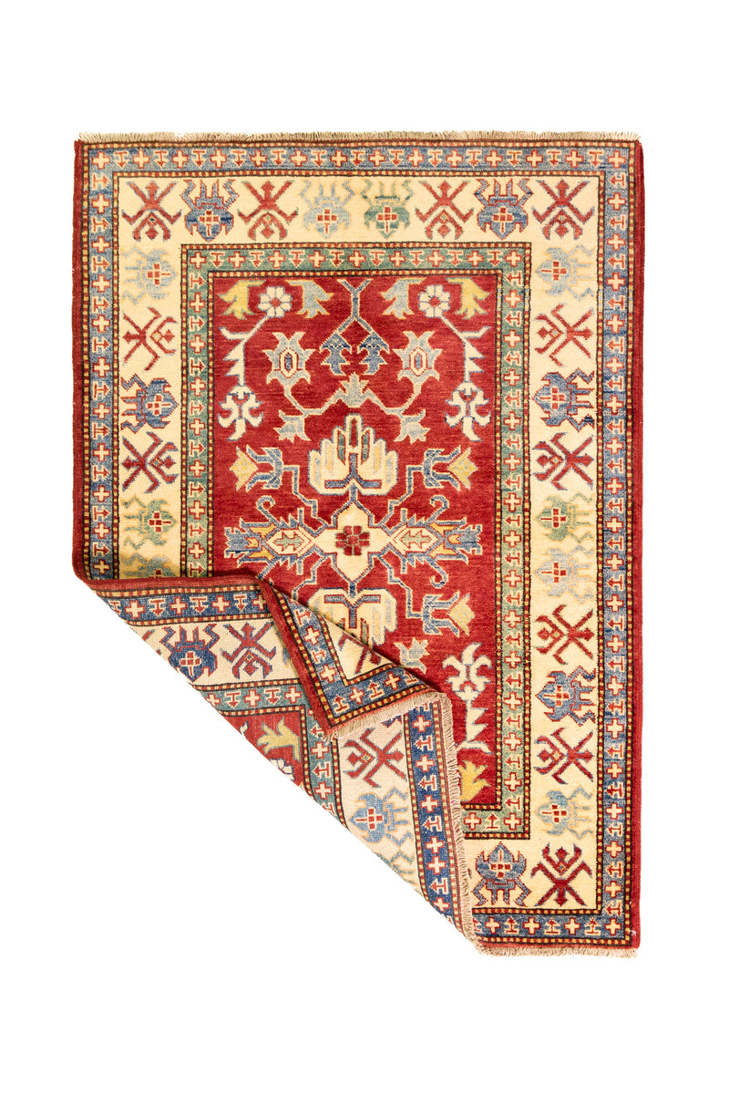 Alfombra Caucasica Kazak rojo con detalles multicolor de 1.17 x 1.63 mts, vista completa con una esquina doblada; el diseño muestra motivos geométricos estilizados sobre un campo rojo y un marco claro con múltiples acentos