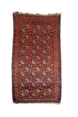 Alfombra Persa Bukara rojo y marrón de 0.85 x 1.45 mts, vista completa vertical; el diseño muestra hileras de medallones ovalados sobre un campo rojo y marrón con guardas geométricas oscuras