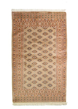 Alfombra Persa Bukara marrón de 0.99 x 1.60 mts, vista completa de la pieza con medallones geométricos repetidos y guardas múltiples que ordenan visualmente el campo central