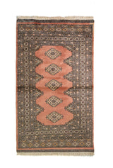 Alfombra Persa Bukara rosado y gris de 0.94 x 1.60 mts, vista completa de la pieza con una secuencia vertical de medallones romboidales rosados sobre un campo gris oscuro
