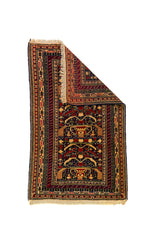 Alfombra Persa Schiraz rojo y beige de 1.42 x 0.86 mts, vista con una esquina doblada para mostrar guarda, reverso y estructura visual