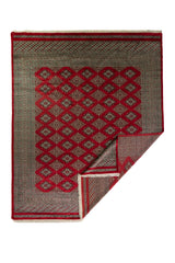 Alfombra Persa Bukara Yamouth rojo de 2.49 x 3.07 mts, vista completa con una esquina doblada; se observan retícula de rombos y motivos geométricos repetidos